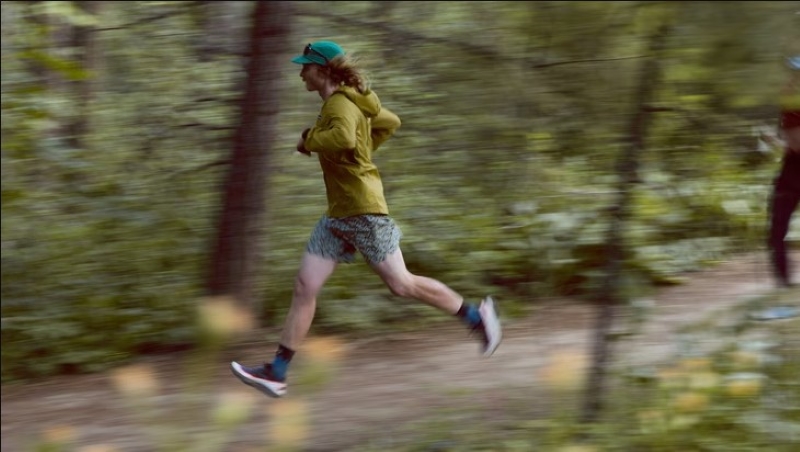 a man running on a forest trail wearing trail running shoes