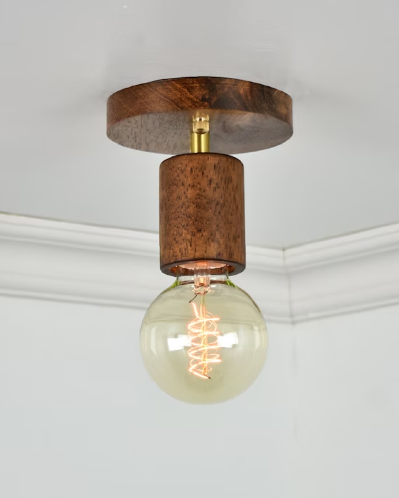 close-up of a ceiling light fixture with a wooden mount and an exposed LED light bulb