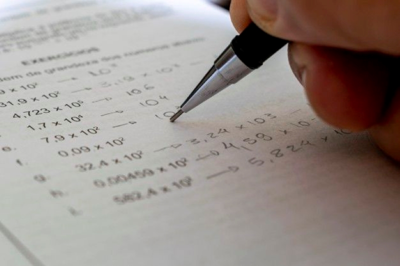 close up of a person solving math problems in a year 10 maths textbook