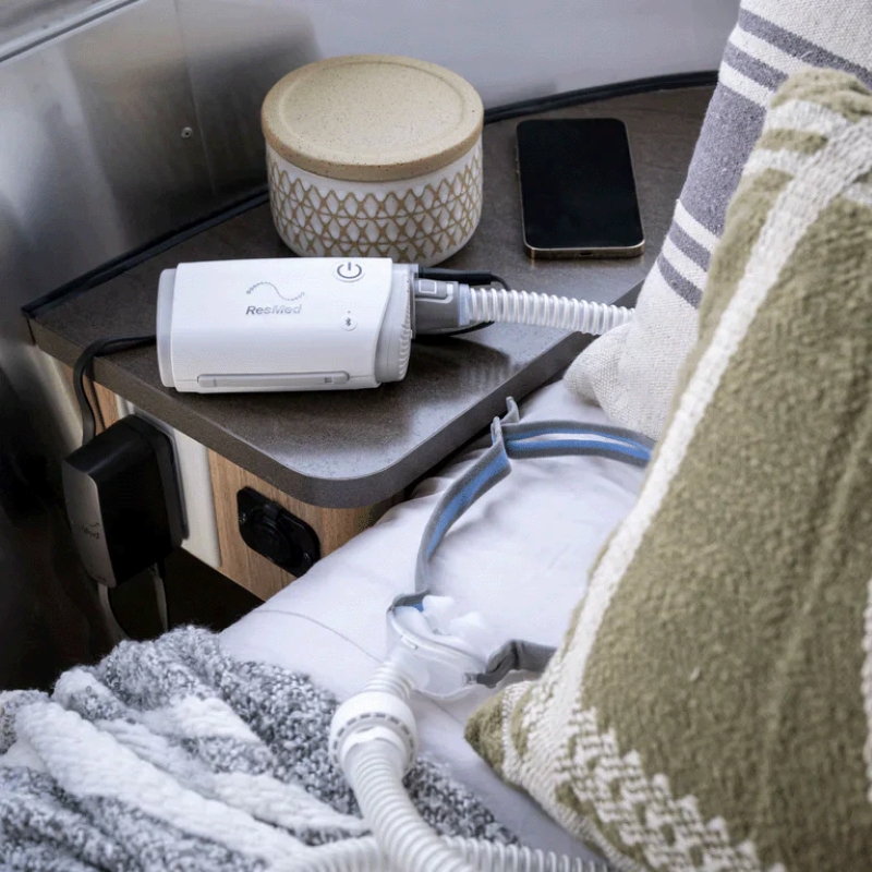 resmed product airmini cpap machine on a nightstand next to a bed