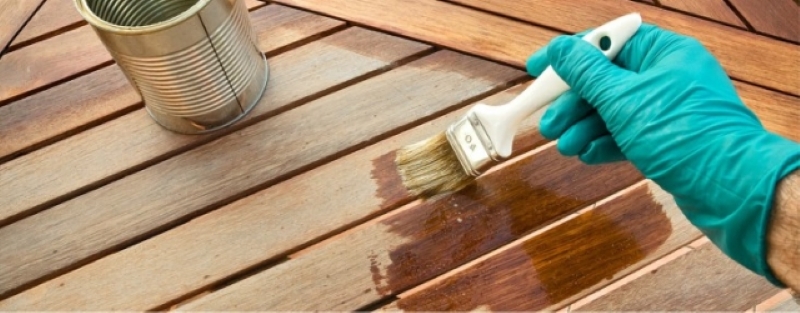 a person applying wood preservatives on a wooden deck